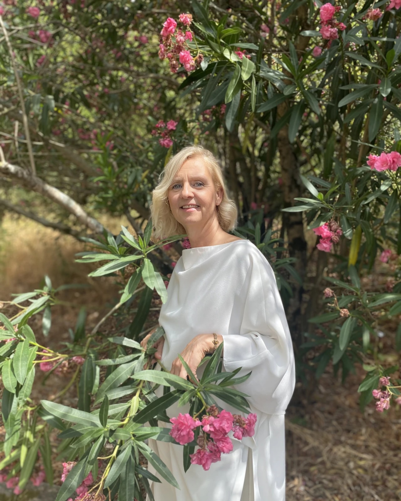Hortênsia Monteiro, de branco, entre flores de aloendro